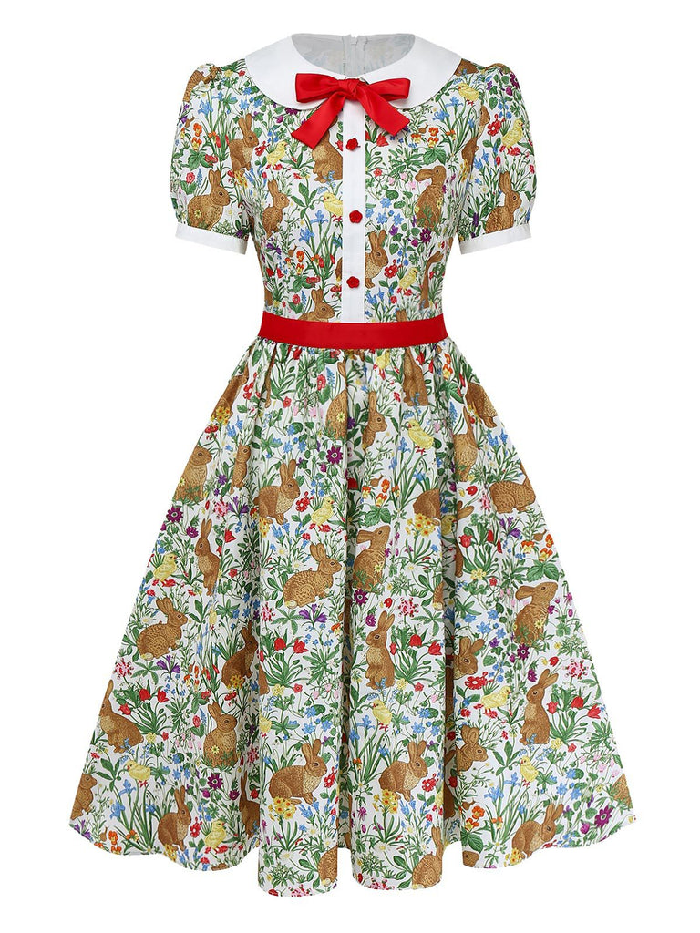 Studioansicht von vorne auf das Kleid mit Hasenmuster, bei dem der rote Taillengürtel und das geknöpfte Oberteil hervorgehoben werden.