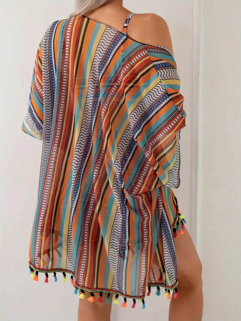 Mehrfarbig gestreiftes Kleid mit Quasten auf einfarbigem Hintergrund