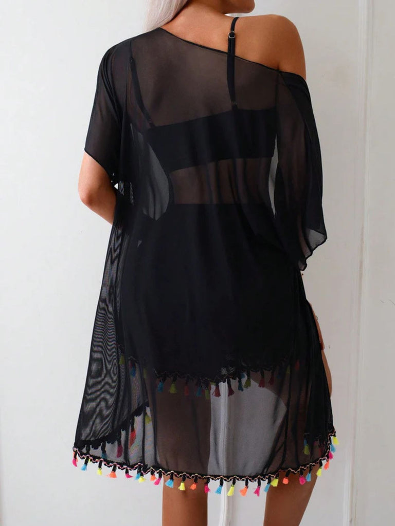 Schwarzes schulterfreies Kleid mit bunten Quasten auf schlichtem Hintergrund