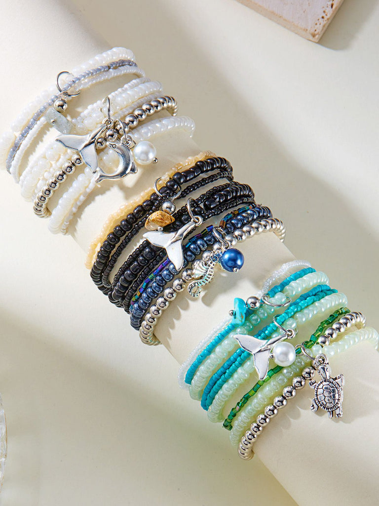 Set aus drei Perlenarmbändern mit Anhängern auf hellem Hintergrund