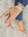 Beige High Heels mit Blumenstickerei, getragen zu zerrissenen Jeans vor einem neutralen Hintergrund