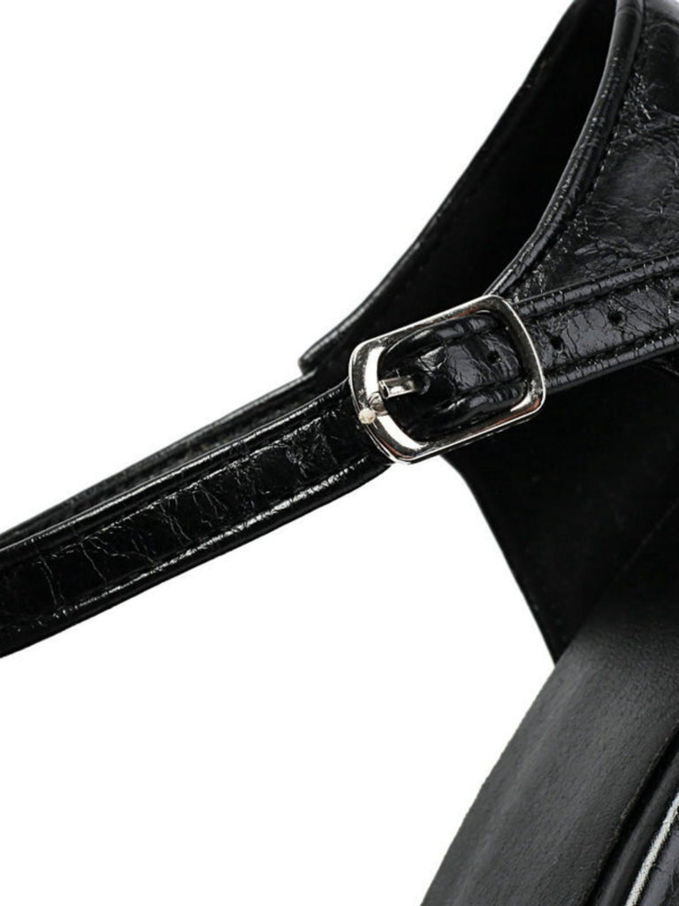 Nahaufnahme eines schwarzen Lederarmbands mit silberner Schnalle vor weißem Hintergrund