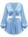 Ein hellblaues, zweiteiliges Loungewear-Set aus seidigem Satin, bestehend aus einem kurzen Oberteil mit Bindeband vorne und langen Ballonärmeln sowie passenden Shorts mit hohem Bund.