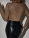 Person mit braunem Langarmshirt mit Sternenmuster und schwarzer Lederhose vor einfarbigem Hintergrund