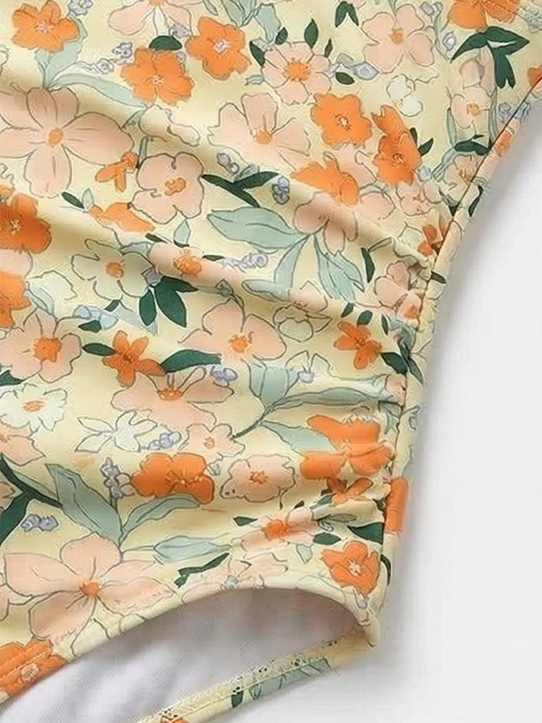 Stoff mit Blumenmuster in Orange, Rosa und Grün auf hellem Hintergrund