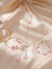 Rosa Schmuckset mit rosa Edelsteinen auf beigefarbenem Stoffhintergrund