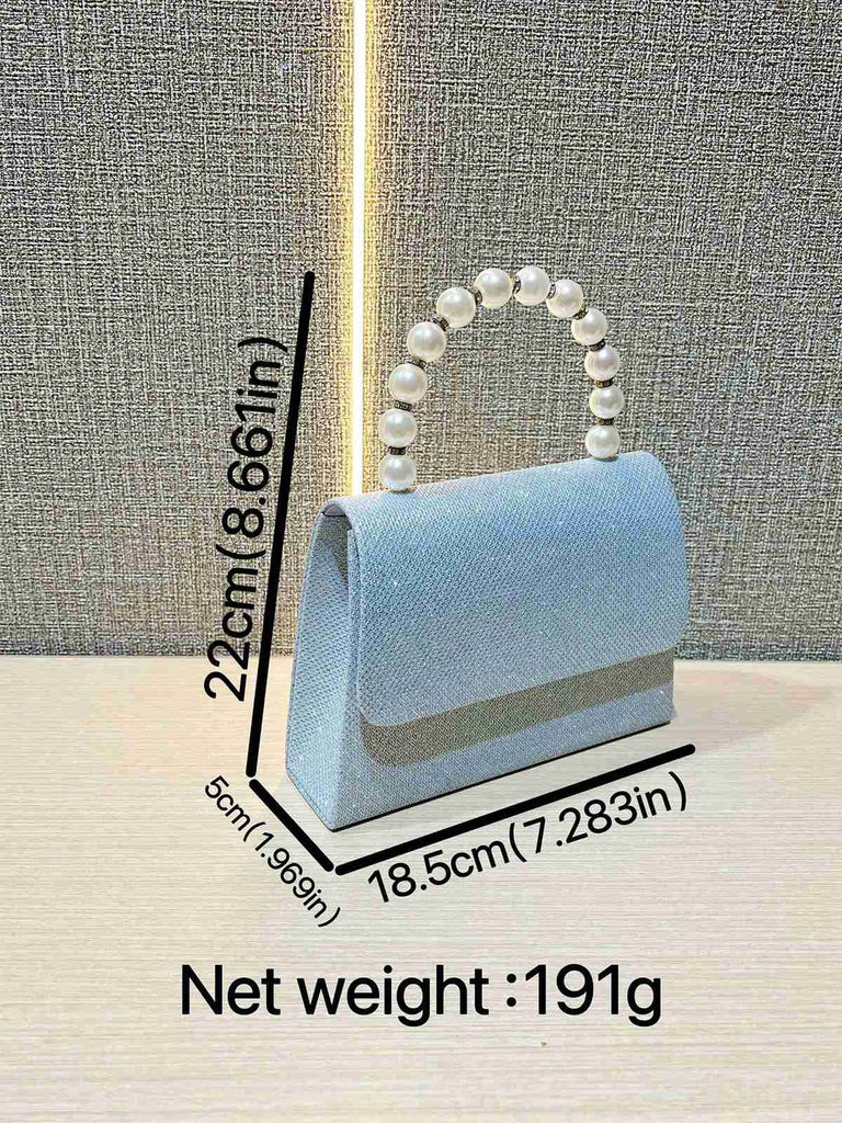 Hellblaue Handtasche mit Perlmuttgriff auf strukturiertem grauen Hintergrund