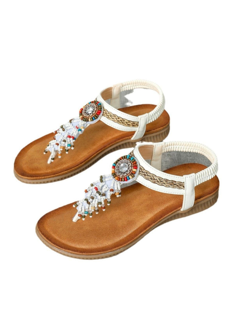 Paar Sandalen mit Zierriemen und Perlen auf weißem Hintergrund