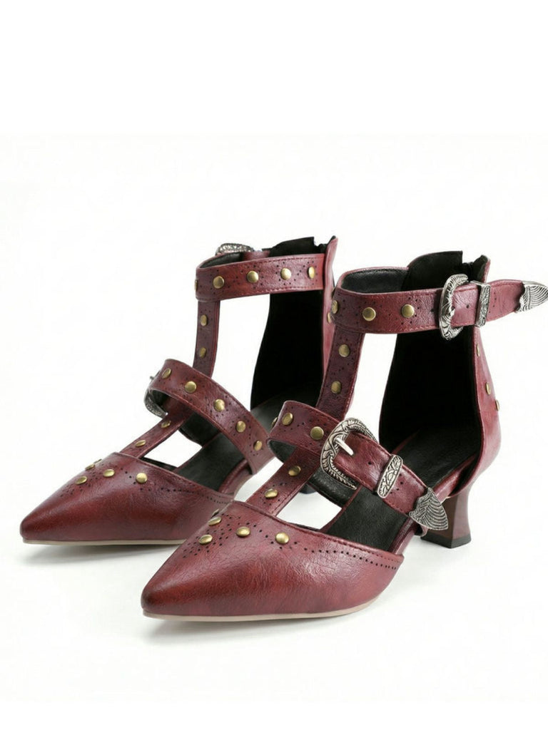 Ein Paar bordeauxrote High Heels mit Nietenbesatz auf weißem Hintergrund