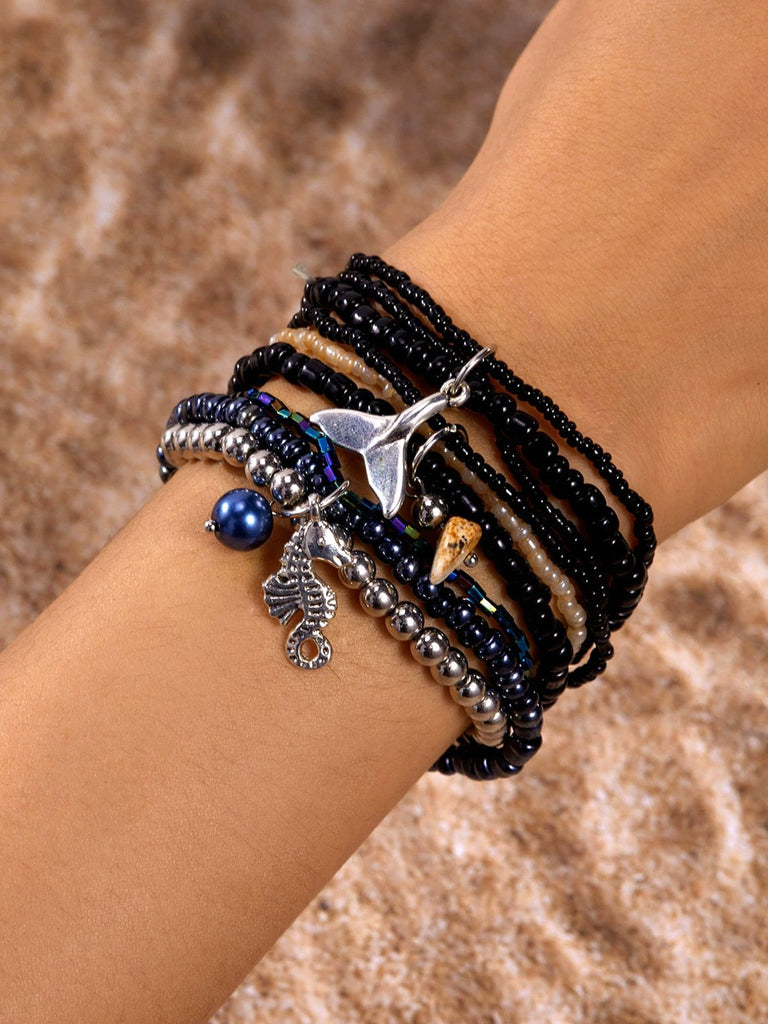 Mehrere Armbänder mit Anhängern an einem Handgelenk vor braunem Hintergrund