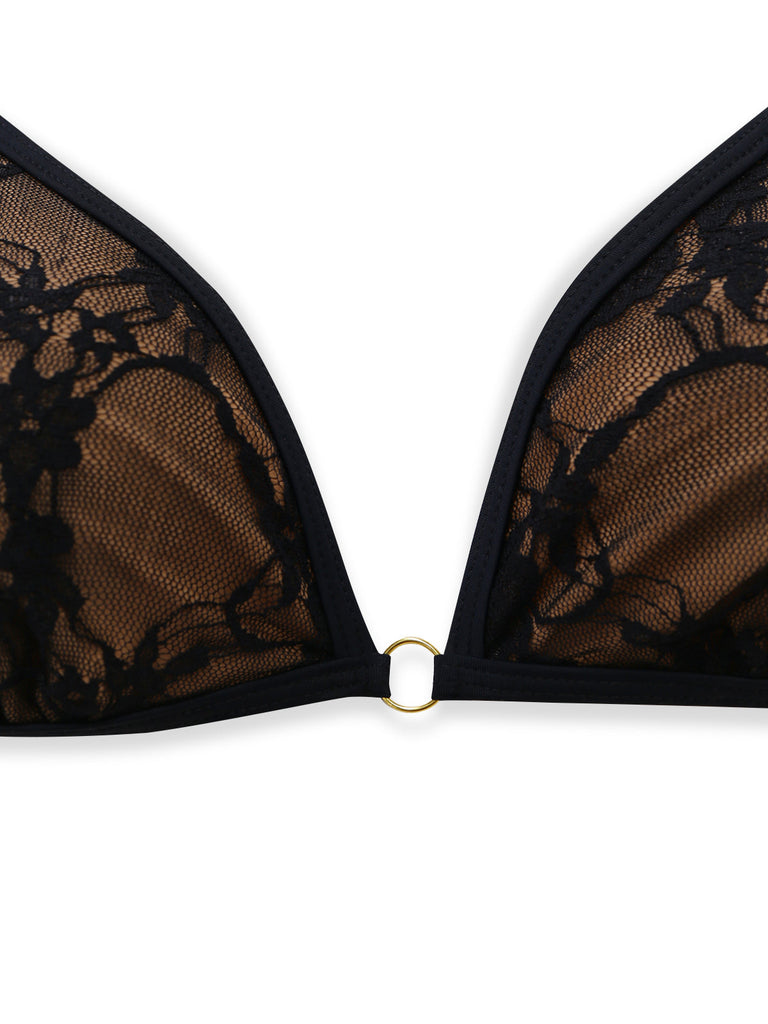 Detailaufnahme des kleinen goldfarbenen Rings, der die dreieckigen Cups des schwarzen Spitzenbikini verbindet.