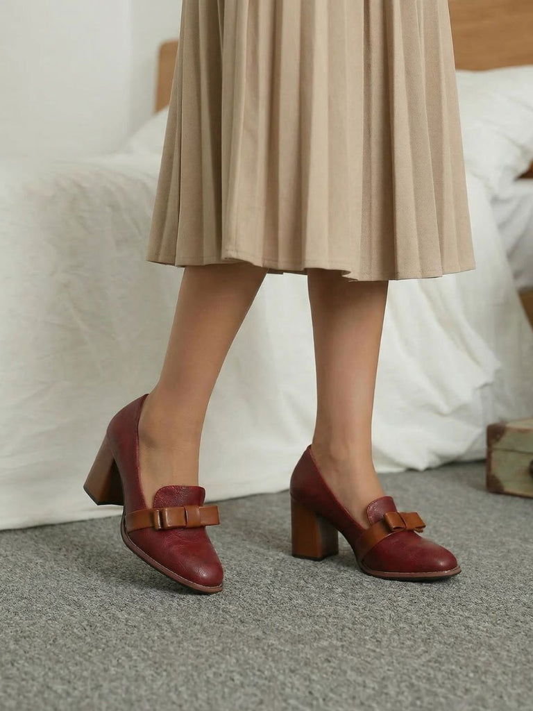 Rote Schuhe mit braunen Schleifenverzierungen, getragen von einer Person in einem beigen Rock.