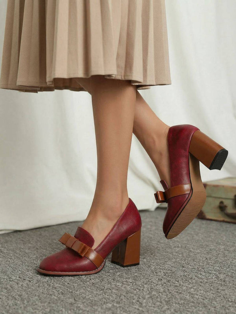 Eine Person in einem beigen Rock trägt rote High Heels mit braunen Sohlen.